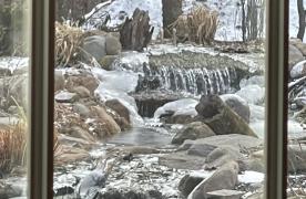 Aquascape grande biofalls waterfalls in winter with ice on stream designed and built by Certified Aquascape Contractor and pond builder Kingdom Landscaping in Sabillasville Maryland view from my dining room window