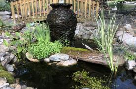 Aquascape stacked slate urn in ecosystem pond with bridge and stream built by Certified Aquascape Contractor and pond builder Kingdom Landscaping in Sabillasville Maryland