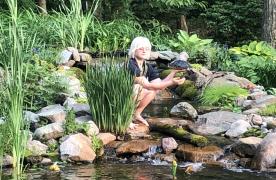 Miranda Tyler with turtle in Aquascape Ecosystem Pond designed and built by Certified Aquascape Contractor and pond builder Kingdom Landscaping in Sabillasville Maryland